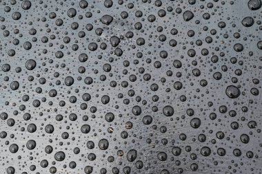 Yağmurdan sonra siyah bir yüzeye su damlaları