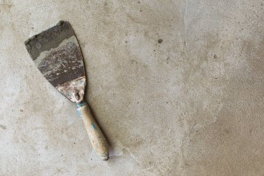 Mala tamiri için inşaat aracı gri-kahverengi çimento ve beton üzerinde yatıyor