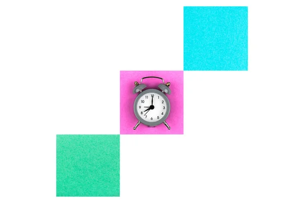 Ρολόι Ένα Ξυπνητήρι Λευκό Φόντο Βρίσκεται Χρωματιστό Χαρτί Φύλλα Πράσινο — Φωτογραφία Αρχείου