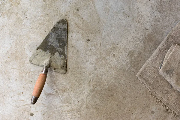 Mala tamiri için inşaat aracı gri-kahverengi çimento ve beton üzerinde yatıyor