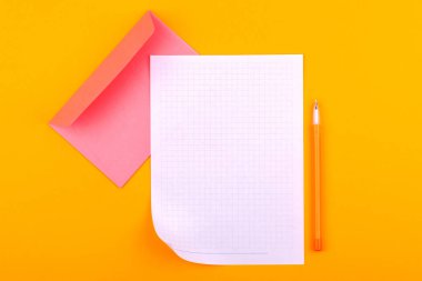 Çizimler, metinler ve notlar için not defteri olan beyaz bir kağıt, sarı bir kalem ve harfler için bir zarfın yanında turuncu bir arka plan üzerinde yer alıyor.