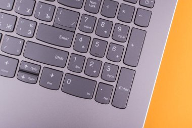 Internet'e bağlı modern klavyesi ve bilgisayar ağı olan gümüş grisi dizüstü bilgisayar, ofisteturuncu bir masaüstünde yer alır