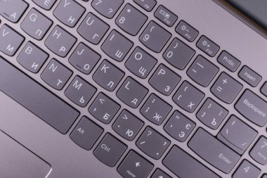 Internet'e bağlı modern klavyesi ve bilgisayar ağı olan gümüş grisi dizüstü bilgisayar, ofisteturuncu bir masaüstünde yer alır