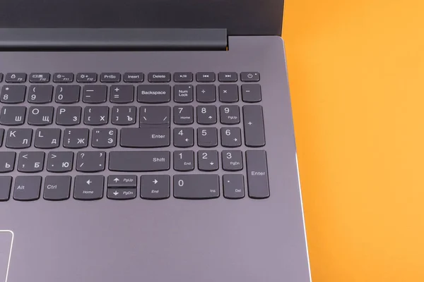インターネットに接続されたモダンなキーボードとコンピュータネットワークを備えた銀色の灰色のラップトップは オフィスのオレンジ色のデスクトップ上にあります — ストック写真