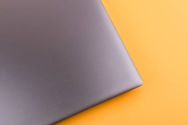 Internet'e bağlı modern klavyesi ve bilgisayar ağı olan gümüş grisi dizüstü bilgisayar, ofisteturuncu bir masaüstünde yer alır