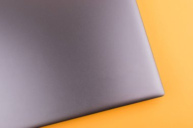 Internet'e bağlı modern klavyesi ve bilgisayar ağı olan gümüş grisi dizüstü bilgisayar, ofisteturuncu bir masaüstünde yer alır