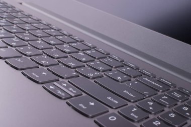 Internet'e bağlı modern klavyesi ve bilgisayar ağı olan gümüş grisi dizüstü bilgisayar, ofisteturuncu bir masaüstünde yer alır