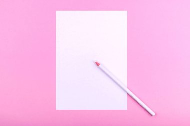 Pembe bir arka plan üzerinde yatan notlar, metinler, çizimler ve notlar için beyaz bir kağıt levha yanında beyaz bir kalem