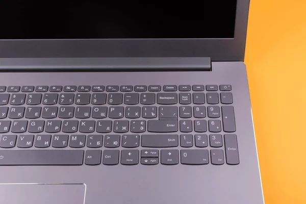 インターネットに接続されたモダンなキーボードとコンピュータネットワークを備えた銀色の灰色のラップトップは オフィスのオレンジ色のデスクトップ上にあります — ストック写真