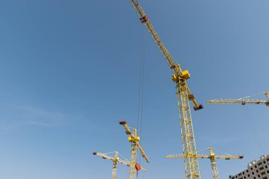 Birkaç sarı yüksek katlı inşaat vinçler mimari tasarıma göre metal, beton ve tuğla modern teknolojileri kullanarak çok katlı çok katlı konut binaları inşa