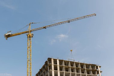 Gökyüzüne karşı yüksek katlı inşaat vinç bir apartman veya ofis merkezi olacak metal, beton ve tuğla, modern teknolojiyi kullanarak çok katlı bir bina inşa ediyor