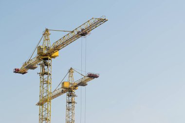 Mavi gökyüzüne karşı sarı bir yüksek katlı bina vinç bir mimari projeye göre metal, beton ve tuğla modern teknolojileri kullanarak çok katlı apartmanlar inşa