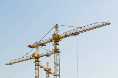 Mavi gökyüzüne karşı sarı bir yüksek katlı bina vinç bir mimari projeye göre metal, beton ve tuğla modern teknolojileri kullanarak çok katlı apartmanlar inşa