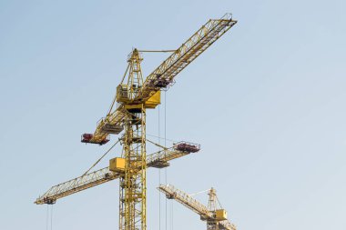 Mavi gökyüzüne karşı sarı bir yüksek katlı bina vinç bir mimari projeye göre metal, beton ve tuğla modern teknolojileri kullanarak çok katlı apartmanlar inşa