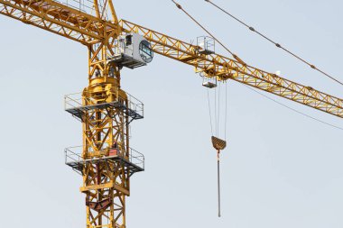 Mavi gökyüzüne karşı sarı bir yüksek katlı bina vinç bir mimari projeye göre metal, beton ve tuğla modern teknolojileri kullanarak çok katlı apartmanlar inşa