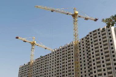 Birkaç sarı yüksek katlı inşaat vinçler mimari tasarıma göre metal, beton ve tuğla modern teknolojileri kullanarak çok katlı çok katlı konut binaları inşa