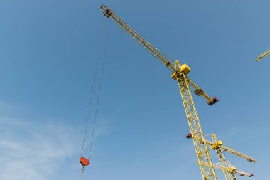 Birkaç sarı yüksek katlı inşaat vinçler mimari tasarıma göre metal, beton ve tuğla modern teknolojileri kullanarak çok katlı çok katlı konut binaları inşa