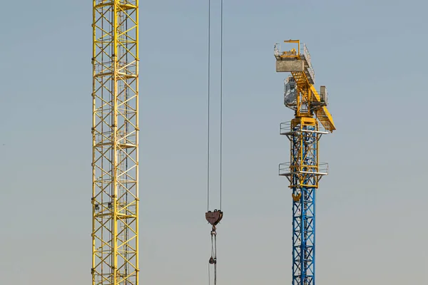 根据建筑项目 一座面向蓝天的黄色高层建筑起重机使用现代金属 混凝土和砖块技术建造多层公寓楼 — 图库照片