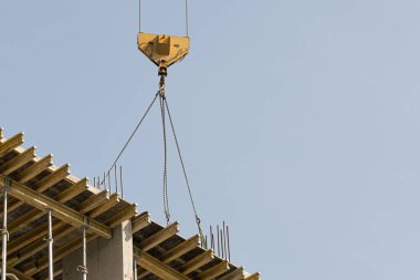 Mavi gökyüzüne karşı sarı bir yüksek katlı bina vinç bir mimari projeye göre metal, beton ve tuğla modern teknolojileri kullanarak çok katlı apartmanlar inşa