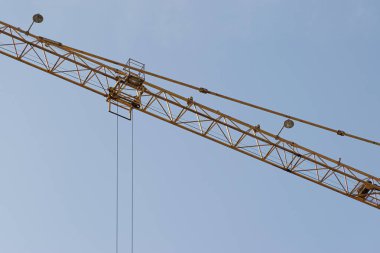 Mavi gökyüzüne karşı sarı bir yüksek katlı bina vinç bir mimari projeye göre metal, beton ve tuğla modern teknolojileri kullanarak çok katlı apartmanlar inşa