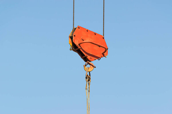 A yellow high-rise building crane against a blue sky builds multi-storey apartment buildings using modern technologies of metal, concrete and brick according to an architectural project