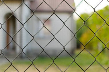 Hırsızlar ve hırsıza karşı güvenlik için örgüyapılmış bir metal çit ile çevrili doğada Kır evi