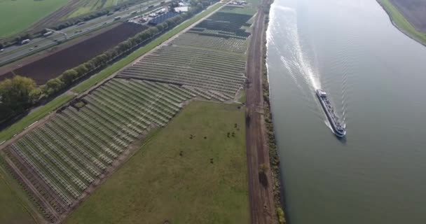 帆船で川の周りの未完成のソーラーパネルフィールドの航空写真 — ストック動画