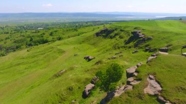 Tepenin havadan görünümü, kırsal alan, doğal dağ taşları ve çim