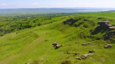 Tepenin havadan görünümü, kırsal alan, doğal dağ taşları ve çim