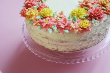 krem renkli çiçekler bir stand ile lezzetli beyaz pasta