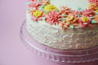 krem renkli çiçekler bir stand ile lezzetli beyaz pasta