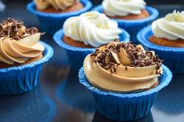 cupcakes in blue molds capsules with different creams