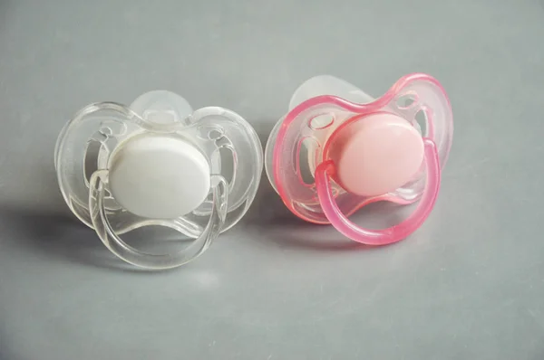 baby pacifiers white and pink on a gray background. nipples.