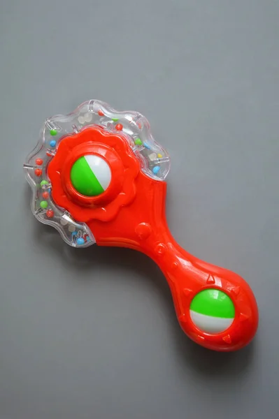 緑色のビーズと要素を持つ赤い子供のおもちゃ 灰色の背景にガラガラ — ストック写真