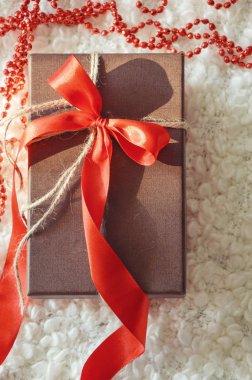 Kırmızı kurdeleli güzel bir hediye kutusu. Hediye için kutu. Beyaz, rahat ekose. Yeni yıl, Noel. Tatil arifesinde.