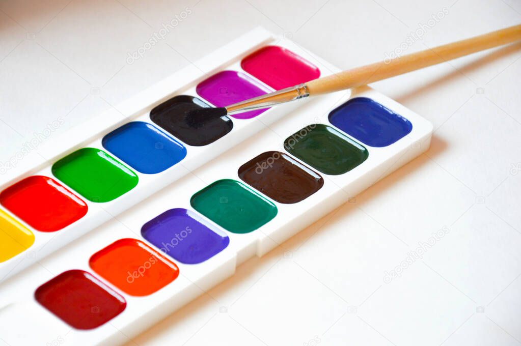 watercolors and a paintbrush. bright colors on a white background. accessories for artists, creativity.