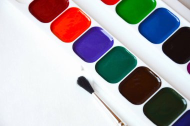 Suluboya ve boya fırçası. Beyaz arka planda parlak renkler. sanatçılar için aksesuarlar, yaratıcılık.