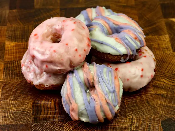 Kiraz jöleli donut yığını ve ahşap kesme tahtasının üzerinde mor ve pembe çizgili jöle. Lezzetli fırınlanmış yemekler, buzlu ve yemeye hazır.!