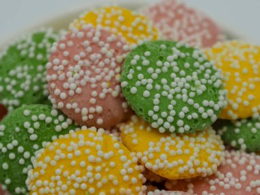 Pastel renkli, yeşil, sarı ve pembe nane şekerleriyle kaplı beyaz nokta parçacıkları..