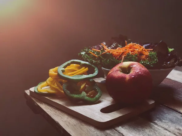 stack of sliced bell peppers with salad bowl and nectarine on table edge