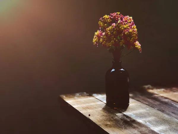 bottle with bouquet on rustic wooden table in daylight