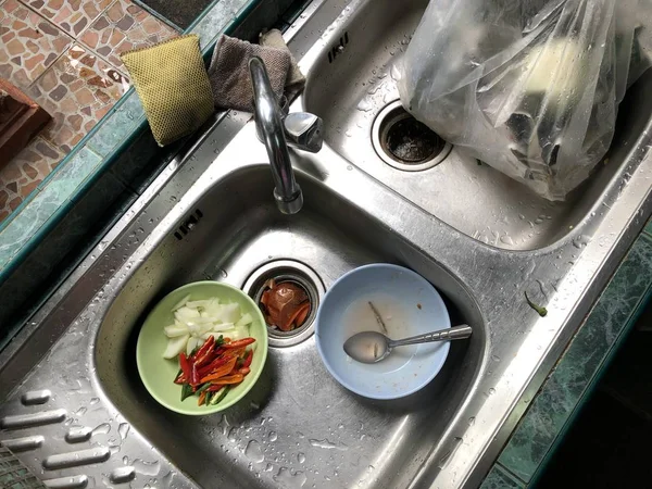 dirty plates with food garbage in kitchen sink