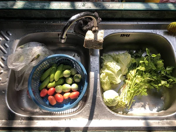 fresh vegetables in kitchen sink and plastic bowl