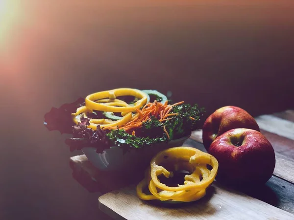 Lezzetli sebze salatası, Sarı ve yeşil tatlı biber, Yeşil Meşe marul, Kırmızı Meşe marul, dilimlenmiş havuç, eski ahşap plakalar taze elma, lens parlama 