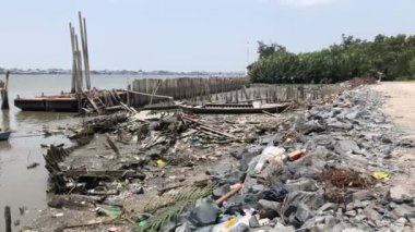 Rubbish and pollution, trash, local fishing boat wrecks on stone dam along the way at estuary, river, lake, sea. Environmental pollution, Samutsakorn, Thailand, 2019.