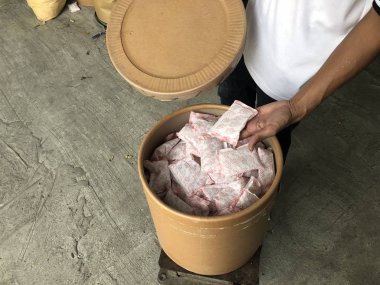 erkek el depoda kahverengi kağıt tankı üzerinde kurutucu silika jel paketi tutarak