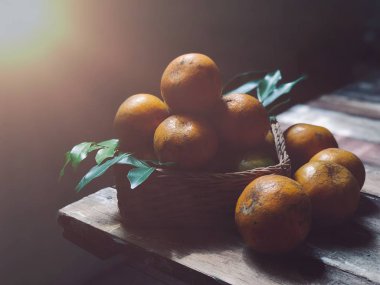 Eski ahşap masa üzerinde hasır sepet yaprakları ile taze mandalina 