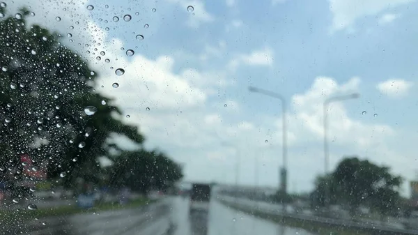 汽车挡风玻璃上的雨滴 模糊的光线背景 城市的交通在雨天 五颜六色的波克 — 图库照片