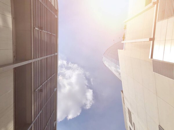 Tops of two modern buildings with background of white fluffy clouds in blue sky at sunny day, ant eye view