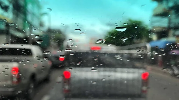 車のフロントガラスに雨滴 ぼやけた光の背景 雨の日に街のトラフィック カラフルなボケ — ストック写真